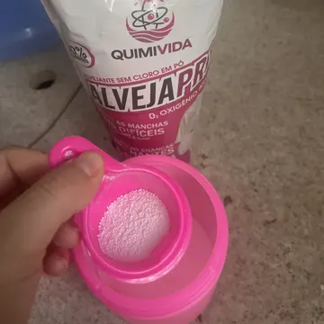 Copo dosador com grânulos de percarbonato, ao lado do pacote